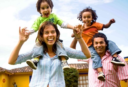 happy Mexican family with kids riding on parent's shoulders